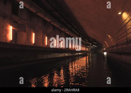 Beleuchteter Betontunnel mit Wasser. Verlassener unterirdischer U-Boot-Stützpunkt aus der UdSSR in Balaklava, Krim Stockfoto