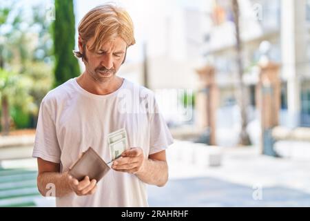Ein junger blonder Mann mit Dollars auf der Straße Stockfoto