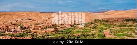 Das üppige fruchtbare Ackerland des Draa-Tals ist umgeben von neuer Stadtentwicklung und der trockenen Bergregion Jebel Sarho im Süden Marokkos. Stockfoto