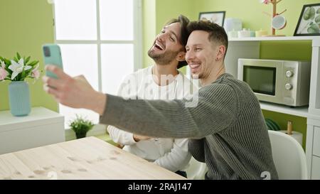 Zwei Männer, die ein Selfie-Foto mit dem Smartphone machen und ein Glas Wein im Speisesaal trinken Stockfoto