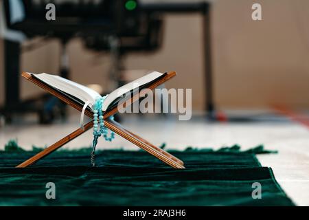 Heiliger Koran mit Rosenkranzperlen auf Holzständer Stockfoto