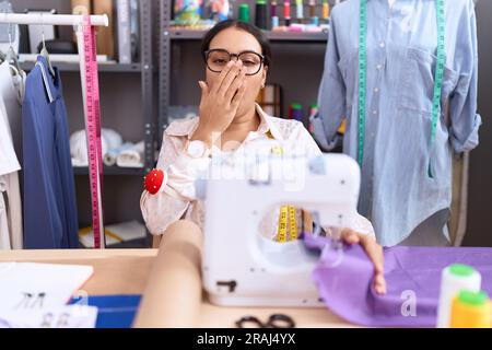 Eine junge arabische Schneiderin, die im Atelier arbeitete, langweilte sich, indem sie den Mund mit der Hand bedeckte. Ruhelosigkeit und Schläfrigkeit. Stockfoto