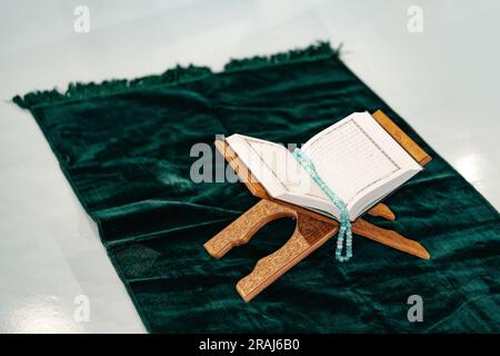 Heiliger Koran mit Rosenkranzperlen auf Holzständer Stockfoto