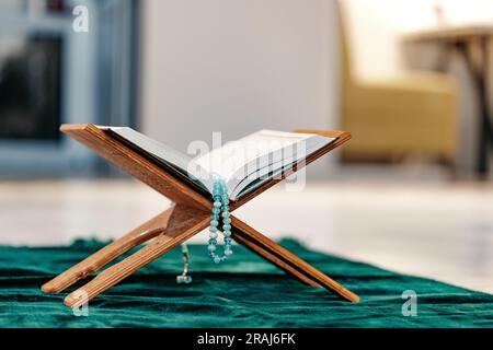 Heiliger Koran mit Rosenkranzperlen auf Holzständer Stockfoto