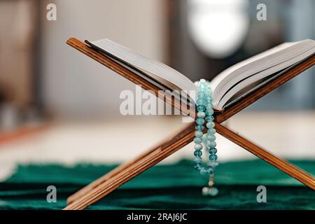 Heiliger Koran mit Rosenkranzperlen auf Holzständer Stockfoto