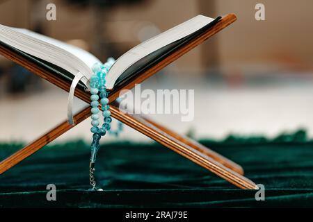 Heiliger Koran mit Rosenkranzperlen auf Holzständer Stockfoto