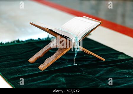 Heiliger Koran mit Rosenkranzperlen auf Holzständer Stockfoto