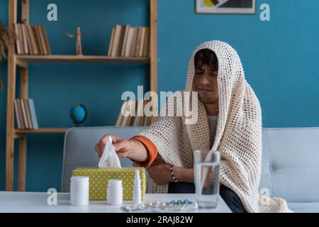 Der kranke arabische Typ sitzt auf der Couch fühlt sich ungesund, leidet an Rhinitis snuffles, hat Atemwegsinfektion Stockfoto