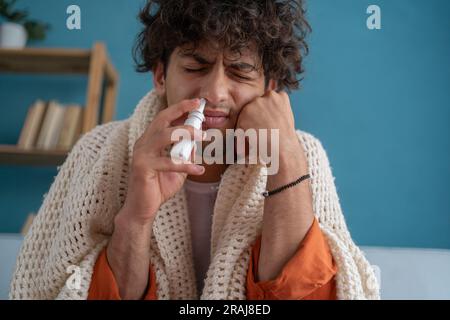 Krankheit und Krankheitskonzept. Ein hübscher araber, der sich krank fühlt, tropft Nasentropfen in die verstopfte Nase. Sinusitisbehandlung. Stockfoto