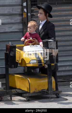 Chassidische jüdische Kinder, die Geschwister zu sein scheinen, auf einer Fahrt mit dem Auto. In Brooklyn, New York, Sommer 2023. Stockfoto