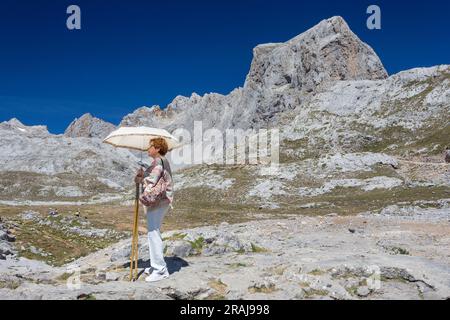 Frau mit Sonnenschirm im Fuente De im Picos de Europa und Nationalpark in der Nähe der Bergstation „El Cable“, zu der eine Seilbahn fährt. Stockfoto