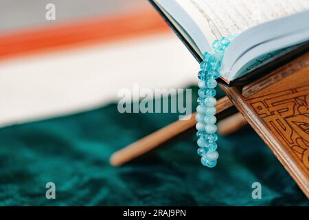 Heiliger Koran mit Rosenkranzperlen auf Holzständer Stockfoto