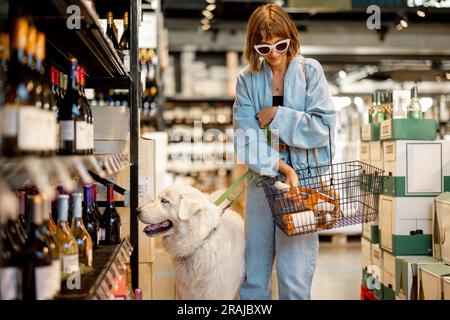Eine Frau besucht mit ihrem Hund einen Weinladen Stockfoto