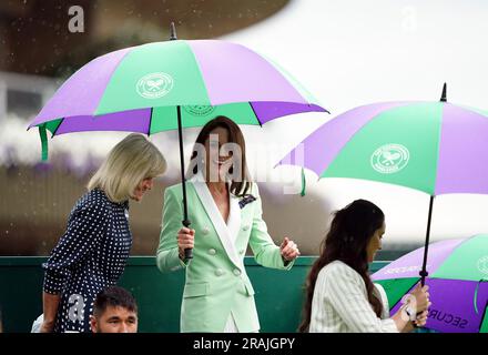 Die Prinzessin von Wales verlässt den Hof unter einem Schirm mit Deborah Jevans und Laura Robson, nachdem das Spiel zwischen Katie Boulter und Daria Saville am zweiten Tag der Wimbledon-Meisterschaft 2023 im All England Lawn Tennis and Croquet Club in Wimbledon unterbrochen wurde. Bilddatum: Dienstag, 4. Juli 2023. Stockfoto