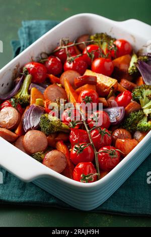 Im Ofen gebackenes Gemüse und Würstchen, gesundes Mittagessen, Süßkartoffel Zwiebel Tomate Brokkoli Stockfoto