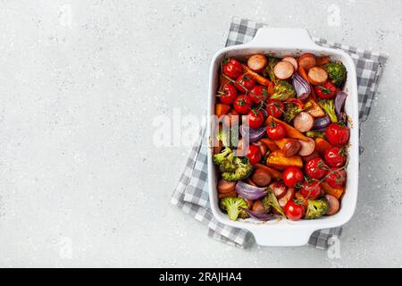 Im Ofen gebackenes Gemüse und Würstchen, gesundes Mittagessen, Süßkartoffel Zwiebel Tomate Brokkoli Stockfoto