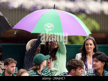 Die Prinzessin von Wales unter einem Schirm mit Deborah Jevans vor dem Regen spielt im Spiel zwischen Katie Boulter und Daria Saville am zweiten Tag der Wimbledon Championships 2023 im All England Lawn Tennis and Croquet Club in Wimbledon. Bilddatum: Dienstag, 4. Juli 2023. Stockfoto