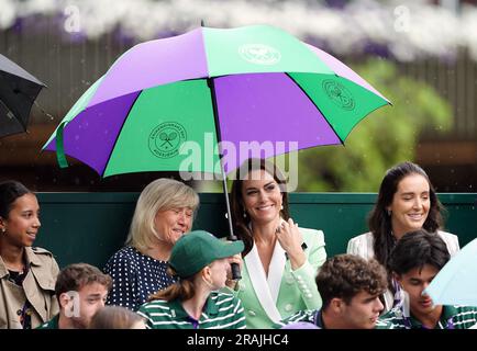 Die Prinzessin von Wales unter einem Schirm mit Deborah Jevans vor dem Regen spielt im Spiel zwischen Katie Boulter und Daria Saville am zweiten Tag der Wimbledon Championships 2023 im All England Lawn Tennis and Croquet Club in Wimbledon. Bilddatum: Dienstag, 4. Juli 2023. Stockfoto