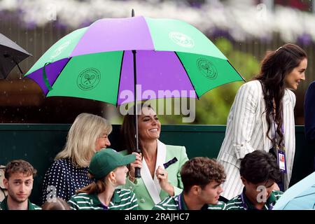 Die Prinzessin von Wales unter einem Schirm mit Deborah Jevans vor dem Regen spielt im Spiel zwischen Katie Boulter und Daria Saville am zweiten Tag der Wimbledon Championships 2023 im All England Lawn Tennis and Croquet Club in Wimbledon. Bilddatum: Dienstag, 4. Juli 2023. Stockfoto