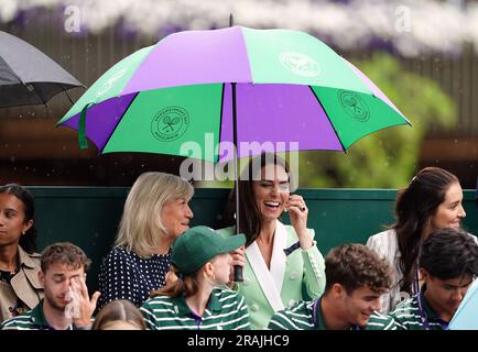 Die Prinzessin von Wales unter einem Schirm mit Deborah Jevans vor dem Regen spielt im Spiel zwischen Katie Boulter und Daria Saville am zweiten Tag der Wimbledon Championships 2023 im All England Lawn Tennis and Croquet Club in Wimbledon. Bilddatum: Dienstag, 4. Juli 2023. Stockfoto