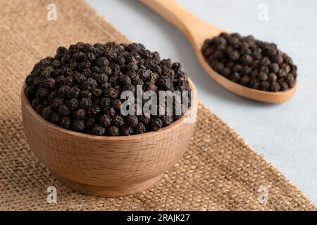 Schwarze Pfefferkörner in einer Holzschüssel Stockfoto