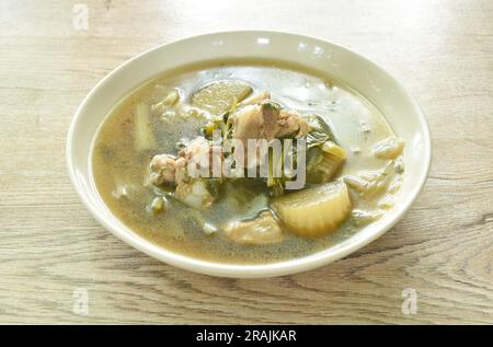 Gekochtes Mischgemüse mit Schweineknochen in schwarzer Sojabohnensuppe auf einem Teller auf dem Tisch Stockfoto