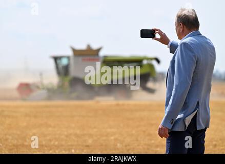 Riethnordhausen, Deutschland. 04. Juli 2023. Joachim Rukwied, Präsident des Deutschen Bauernverbandes, macht ein Foto der Wintergerstenernte auf einem Feld der Universal Agrar GmbH. Der Deutsche Bauernverband gibt eine erste Prognose für die diesjährige Ernte vor. In einigen Teilen Deutschlands, einschließlich des fruchtbaren Thüringer Beckens, beginnt die Getreideernte heute. Kredit: Martin Schutt/dpa/Alamy Live News Stockfoto