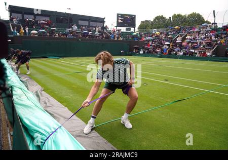 Das Bodenpersonal zieht die Regendecke heraus, während am zweiten Tag der Wimbledon-Meisterschaft 2023 im All England Lawn Tennis and Croquet Club in Wimbledon der Regen stoppt. Bilddatum: Dienstag, 4. Juli 2023. Stockfoto