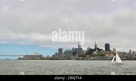 Ruby Princess-Kreuzfahrtschiff mit niedriger Wolke, die oben auf Wolkenkratzern liegt, Blick auf San Francisco, Kalifornien, USA mit einer Yacht Stockfoto