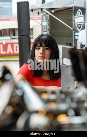 Vertikales Porträt einer jungen lateinin, die an der Theke eines Fast-Food-Trucks steht, in die Kamera schaut und darauf wartet, das Essen zu bestellen. Speicherplatz kopieren. Stockfoto