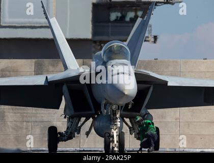 Mittelmeer, Internationale Gewässer. 02. Juli 2023. EIN US-AMERIKANISCHER Navy Sailor bereitet einen F/A-18E Super Hornet Fighter Jet vor, der am Ragin' Bulls of Strike Fighter Squadron 37 befestigt ist, zum Start vom Cockpit an Bord des Flugzeugträgers USS Gerald R. Ford der Nimitz-Klasse, der am 2. Juli 2023 vor der italienischen Küste im Mittelmeer operiert. Kredit: MC2 Nolan Pennington/USA Navy Photo/Alamy Live News Stockfoto