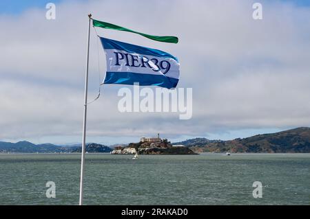 Blick in Richtung Alcatraz Island vom Ende des Pier 39 über die San Francisco Bay mit einer Pier 39 Flagge San Francisco California USA Stockfoto