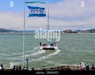 Der Adventure Cat2-Katamaran fährt in Richtung Alcatraz Island ab dem Ende des Pier 39 mit einer Pier 39-Flagge und Touristen aus San Francisco California USA Stockfoto