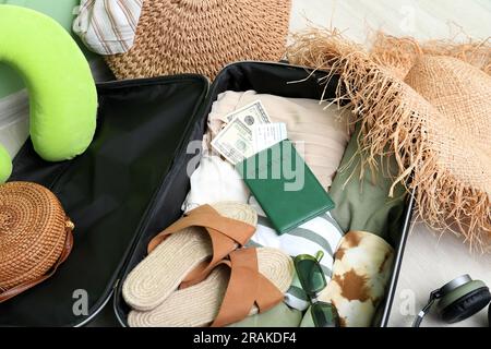 Koffer mit Kleidung, Strandzubehör, Reisepass und Ticket auf dem Boden. Reisekonzept Stockfoto