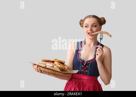 Wunderschöne Oktoberfest-Kellnerin mit Snacks auf hellem Hintergrund Stockfoto