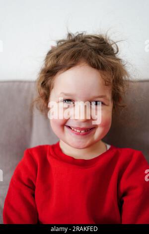 Lustiges kleines lächelndes Mädchen, Kind schaut zu Hause in die Kamera, glückliche Kindheit Stockfoto