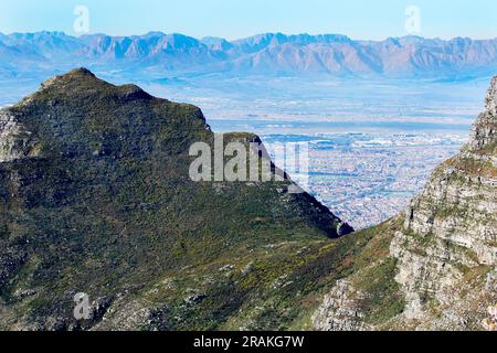 Die Aussicht vom Gipfel des Tafelbergs an einem schönen Wintertag. Auch Blick auf die Rückseite des Tafelbergs aus einem Park in Kapstadt. Stockfoto