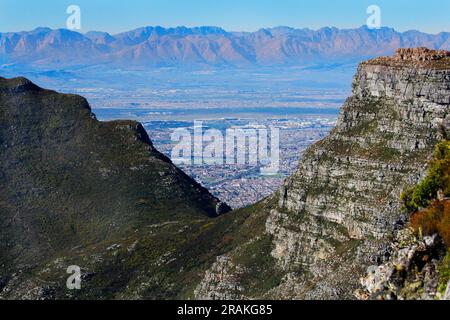 Die Aussicht vom Gipfel des Tafelbergs an einem schönen Wintertag. Auch Blick auf die Rückseite des Tafelbergs aus einem Park in Kapstadt. Stockfoto