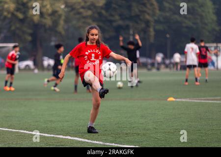 Ein Mädchen übt seine Fußballkünste während eines Abends auf einem Gemeindeplatz in der Innenstadt Stockfoto