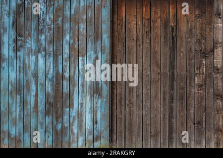 Tore von alten verwitterten Brettern, vertikal angeordnet. Eine Hälfte blau gestrichen. Stockfoto