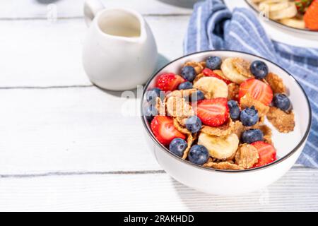 Gesunde Vitamindiät Sommerfrühstück. Cornflakes mit mehreren Körnern, Joghurt oder Milch und Erdbeeren, Blaubeeren, auf dem Küchentisch Kopierraum Stockfoto