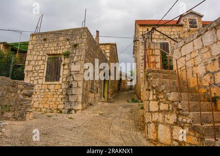 Eine Straße mit historischen Steinhäusern im Dorf Loziscz im Zentrum der Insel Brac in Kroatien Stockfoto