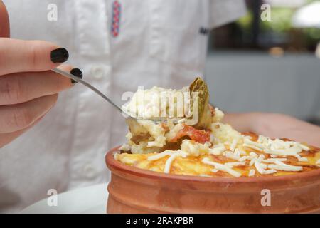 Frau isst traditionelle griechische Moussaka, zubereitet in Tontopf Stockfoto