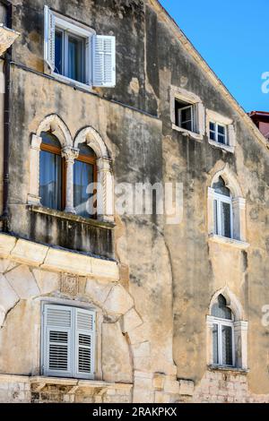 Fassade eines alten Gebäudes mit dekorativen Fenstern in der mittelalterlichen Altstadt von Split innerhalb der Mauern von Diokletianpalast, Split, Dalmatien, Kroatien. Stockfoto