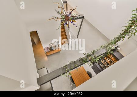 Ein Wohnzimmer mit Pflanzen an der Wand und eine offene Treppe, die in die zweite Etage führt, wie von oben gesehen Stockfoto