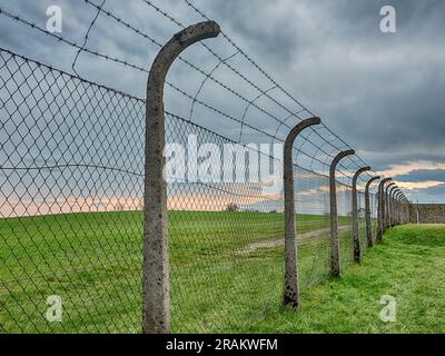 MAUTHAUSEN, ÖSTERREICH - 4. DEZEMBER 2022: Ein elektrifizierter Zaun trennt die Kaserne vom ländlichen Raum des Konzentrationslagers Mauthausen in Stockfoto