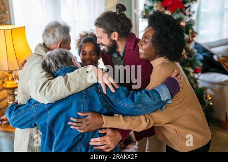 Fröhliche, erweiterte, multiethnische Familie, die Spaß hat, während sie gemeinsam zu Hause Weihnachten feiern. Stockfoto