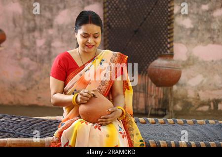 Glückliche ländliche indische Frauen in Saree mit der Piggy Bank in der Hand. Eine Frau mit Ehrgeiz zeigt ihre Liebe zu gespartem Geld für ihre Zukunft, wenn sie ins Ausland geht. Stockfoto