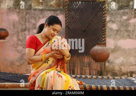 Glückliche ländliche indische Frauen in Saree mit der Piggy Bank in der Hand. Eine Frau mit Ehrgeiz zeigt ihre Liebe zu gespartem Geld für ihre Zukunft, wenn sie ins Ausland geht. Stockfoto