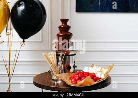Ein luxuriöses Dessertbuffet mit frischem Obst und Schokoladenbrunnen. Farbenfrohes Dessertbuffet für eine luxuriöse Geburtstagsparty. Stockfoto
